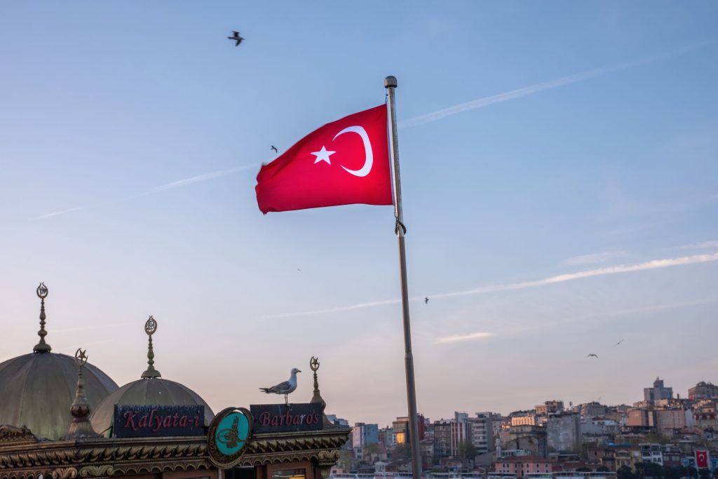 red flag turkey foreground flying seagulls local architectural buildings scaled 1